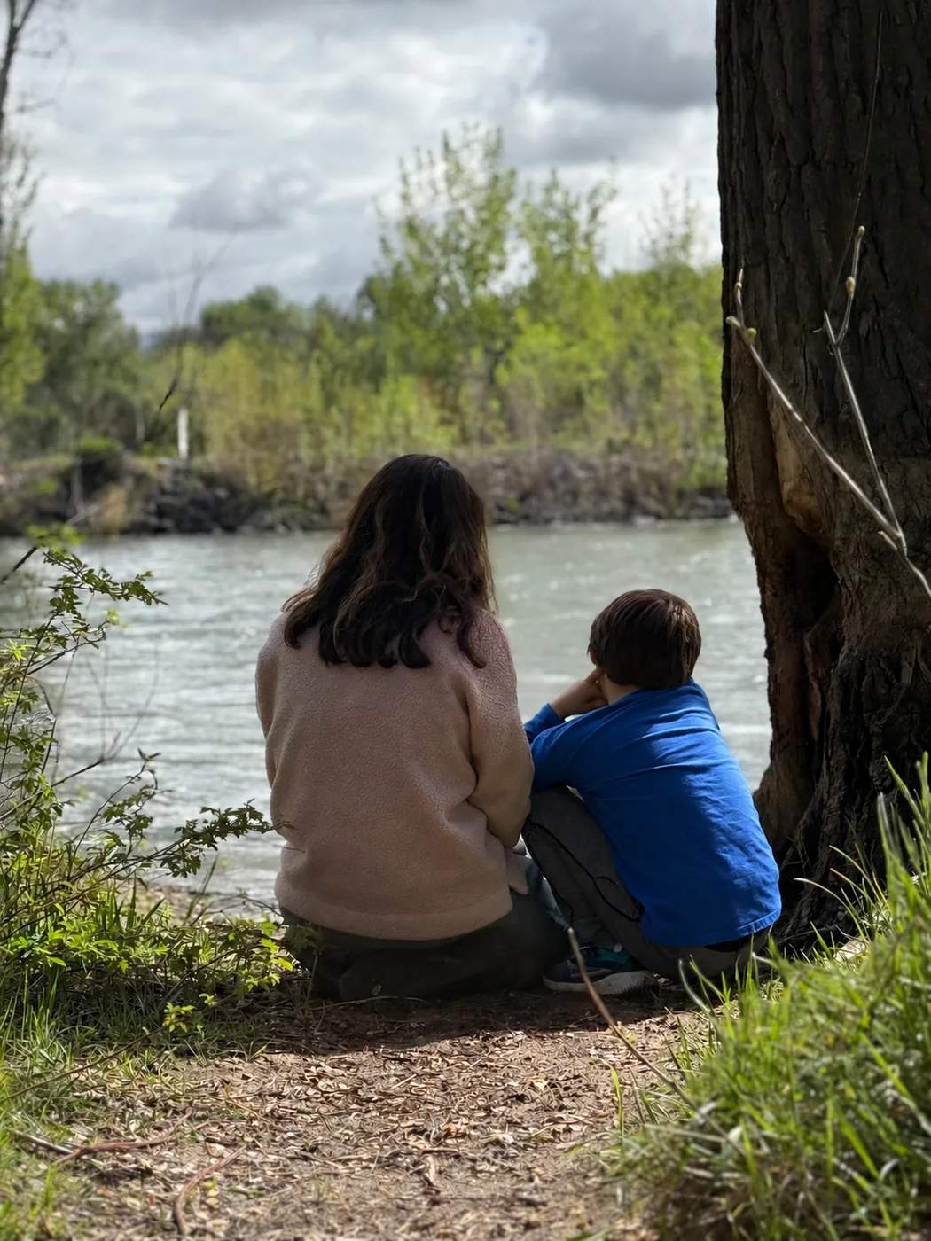A child and therapist sitting together beside the Boise River