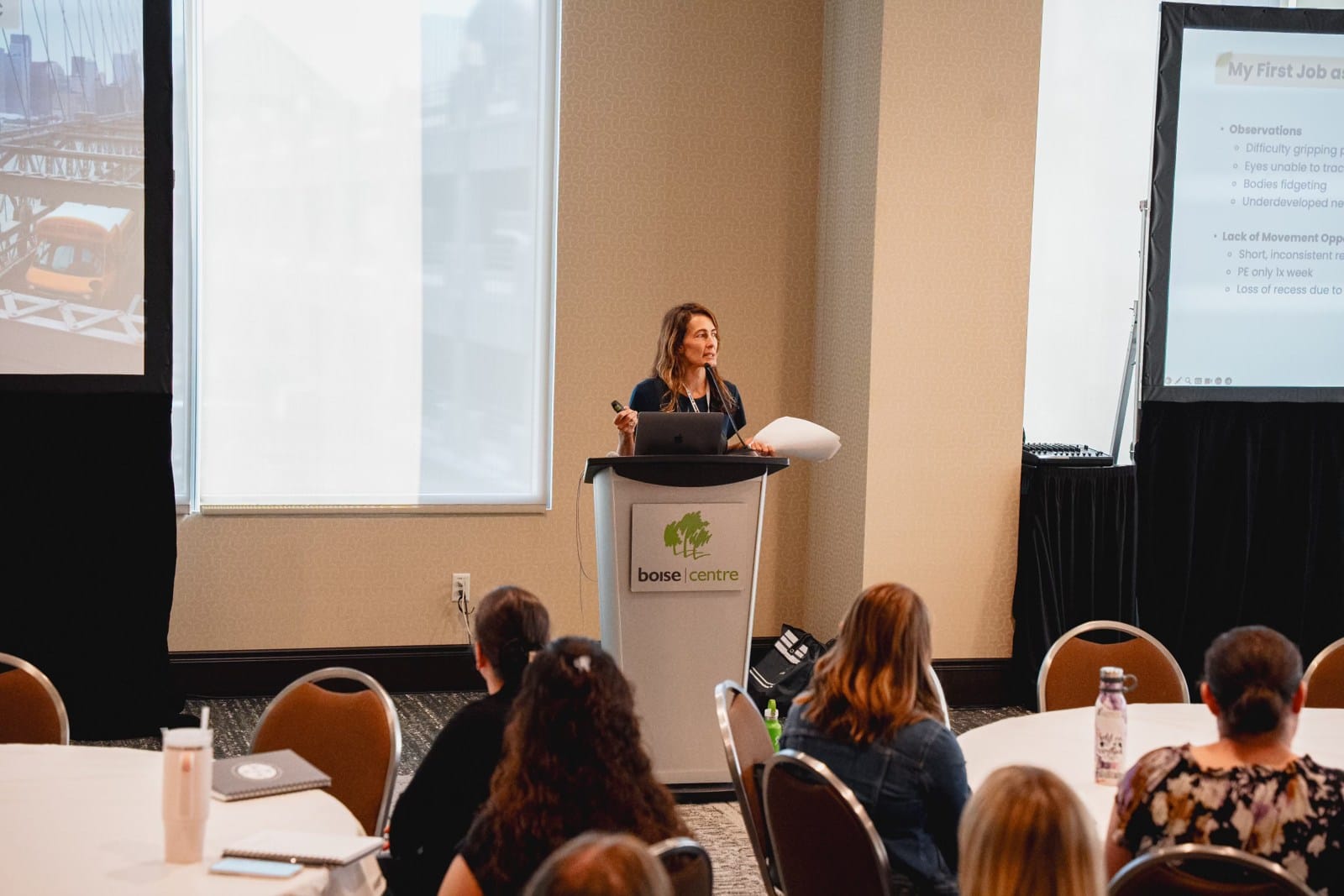 Daniele speaking at a lectern to conference attendees