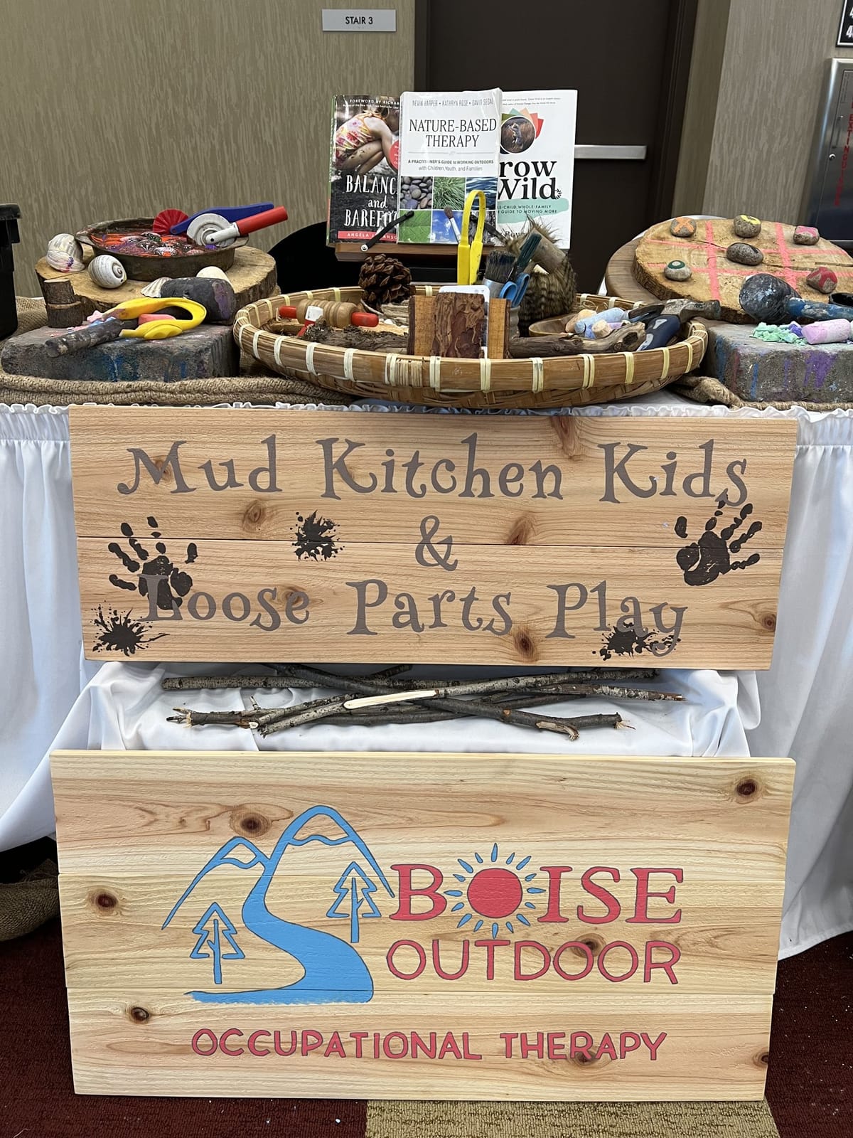 Mud Kitchen Kids and Boise Outdoor OT display with natural play materials and books