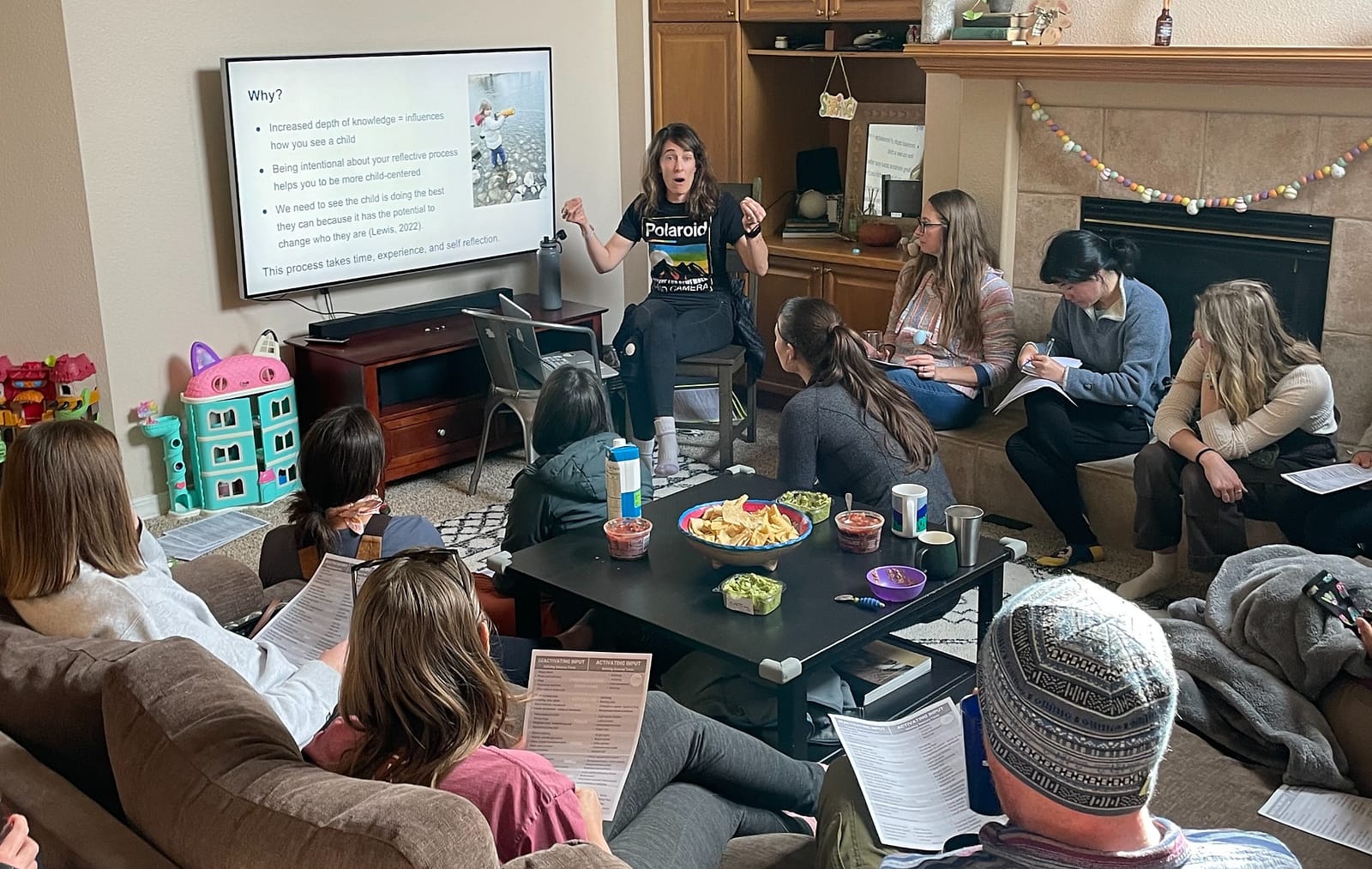 Daniele teaching a group gathered in a living room beside a TV presentation
